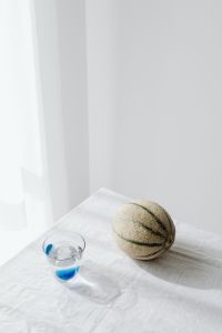Kaboompics - Minimal Melon and Water Glass Still Life on White Tablecloth, Bright Food Editorial