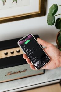 Kaboompics - Black speaker on marble table, white wall, mobile phone in hand