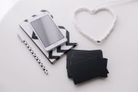 Kaboompics - Overhead Black-and-White Stationery Flat Lay with Smartphone, Geometric Notebook and Heart-Shaped Cable