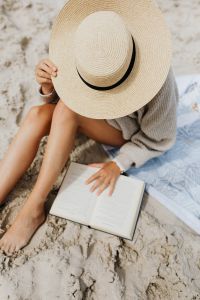 Kaboompics - Woman Reading on a Beach Blanket with an Open Book and Straw Hat