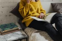 Kaboompics - Woman Reading a Magazine Beside a Stack of Books and Marble Coffee Table