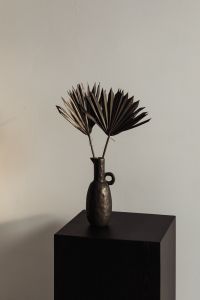 Kaboompics - Two Dried Palm Fronds in a Textured Black Vase on a Pedestal, Neutral Still Life