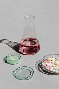 Kaboompics - Pink Laboratory Flask With Glass Dish and Tablets
