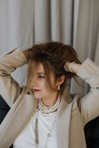 Kaboompics - Woman Styling Her Hair in a Beige Blazer and Pearl Jewelry