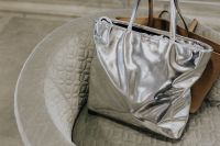 Kaboompics - Silver and Tan Handbags Styled on a Quilted Cream Tub Chair
