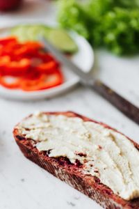 Kaboompics - Hummus Bread Close-Up with Blurred Vegetable Plate and Knife