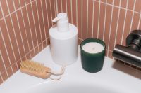 Kaboompics - White Soap Dispenser and Green Candle by Bathtub
