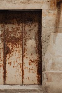 Kaboompics - Rusty Metal Door in an Old Limestone Wall, Distressed Industrial Texture Background