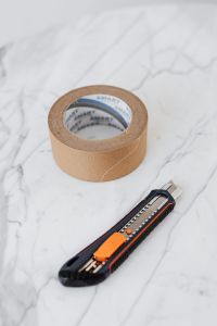 Kaboompics - Masking Tape Roll and Retractable Utility Knife on White Marble, Vertical DIY Background
