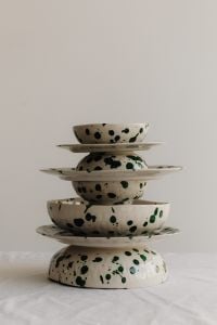 Kaboompics - Stacked Green Splatter Bowls and Plates on a Neutral Linen Table