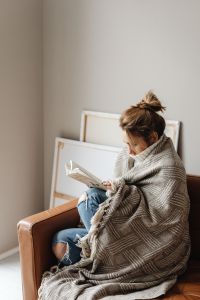 Kaboompics - Cocooning at Home: Woman Reading in a Knit Blanket