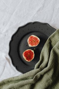 Kaboompics - Vertical Fig Halves on Speckled Black Stoneware with White Linen Copy Space