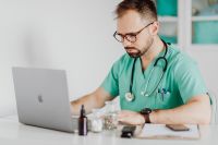 Kaboompics - Doctor Working on Laptop With Medical Supplies
