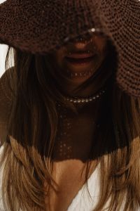 Kaboompics - Portrait under a Straw Hat with Pearl Necklace and Dappled Sunlight