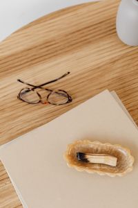 Kaboompics - Tortoiseshell Glasses beside a Beige Book on a Wooden Desk, Minimal Reading Workspace
