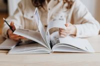 Kaboompics - Woman Turning Book Pages at Wooden Desk