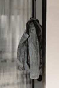 Kaboompics - Black Leather Jacket Hanging by Ribbed Glass