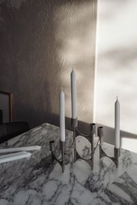 Kaboompics - Chrome Candelabra with Three White Candles and Spares on Marble, Dramatic Light and Shadow
