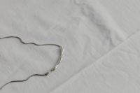 Kaboompics - Silver Chain Necklace Close-Up on White Fabric