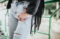 Kaboompics - Blonde woman in a black jacket and ripped jeans by a green handrail