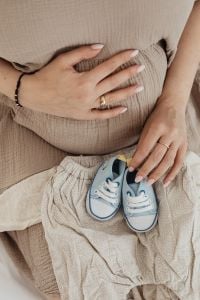 Kaboompics - Pregnant Belly and Baby Shoes on Baby Clothes