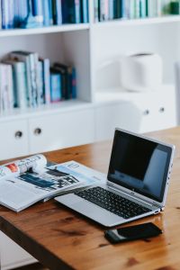 Silver Laptop Home Office Workspace with Smartphone, Camera and Magazine on a Wooden Desk