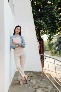 Kaboompics - Asian Woman Holding a Pink Laptop Against a White Wall