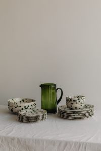 Kaboompics - Green Glass Pitcher and Splatter Dinnerware on a Neutral Table