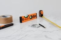 Kaboompics - Home Renovation Tool Flat Lay on White Marble with Level, Tape, Cutter, Pencil and Anchors