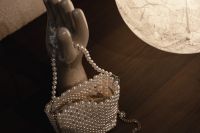 Kaboompics - Wide Still Life of a Pearl Beaded Handbag on a Ceramic Hand Stand and Dark Wood