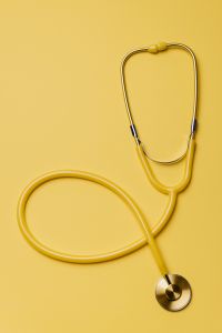Kaboompics - Single Yellow Stethoscope on Bright Yellow Surface, Clean Healthcare Product Photo