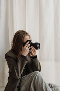 Kaboompics - Young Female Photographer Taking Photo with DSLR in Neutral Studio