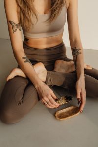 Kaboompics - Seated Woman Holding Smoldering Sage Beside a Small Dish