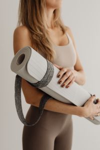 Kaboompics - Woman Holding a Rolled Yoga Mat Across Her Body