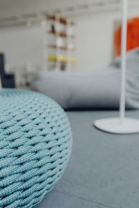Blue Knit Pouf Ottoman in a Minimalist Living Room, Cozy Modern Furniture and Woven Textile Details