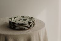 Kaboompics - Green Splatter Plate Stack on a Draped Linen Table