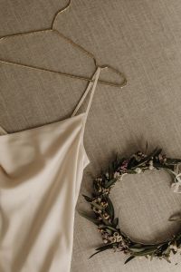 Kaboompics - Satin Wedding Dress on a Gold Hanger with Floral Wreath