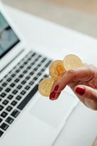 Kaboompics - Bitcoin Coin Held Above Open Laptop