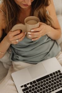 Kaboompics - Close-Up of Hands Holding a Coffee Mug Beside a Laptop at Home