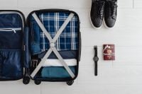 Kaboompics - Overhead Holiday Packing Flat Lay with Open Suitcase, Clothes, Black Shoes and Travel Watch