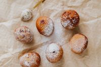 Kaboompics - Scattered Polish Doughnuts with Icing Sugar and Gold Pastry Strainer, Overhead Food Photo