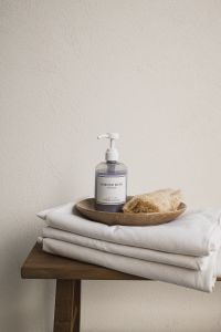 Kaboompics - Wooden Bench with Soap and Loofah on Stacked White Towels