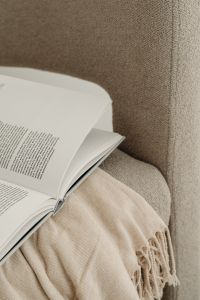 Kaboompics - Close-Up of an Open Book and Fringed Throw on a Beige Armchair
