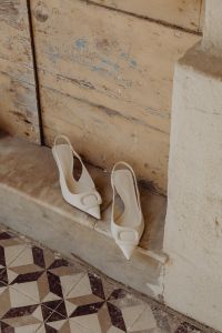 Kaboompics - White high-heeled open-back pumps with front embellishment - Pointed toe - Ankle strap