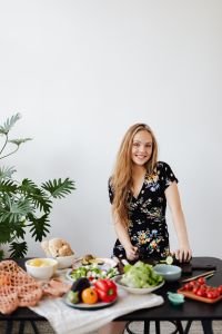 Kaboompics - Smiling Woman Leaning over a Kitchen Counter with Salad Ingredients