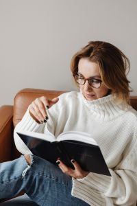 Kaboompics - Woman Reading the Bible in Glasses on a Leather Sofa