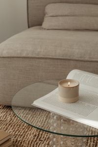 Kaboompics - Beige Candle on Open Book beside Textured Gray Sofa