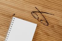 Kaboompics - Open Spiral Notebook and Eyeglasses on a Wooden Desk, Wide Minimal Writing Background