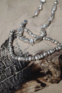 Kaboompics - Silver Necklace Resting on Driftwood