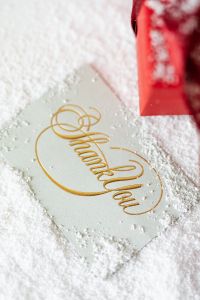 Kaboompics - Gold Thank You Card beside a Red Gift Box in Festive Holiday Styling